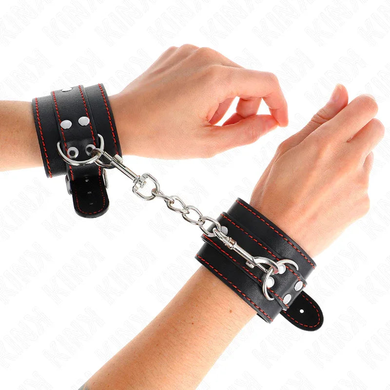 KINK - HANDGELENKFESSELN SCHWARZ MIT ROTEM FUTTER VERSTELLBAR 20-28 CM X 5,5 CM - Vanelion Paradise